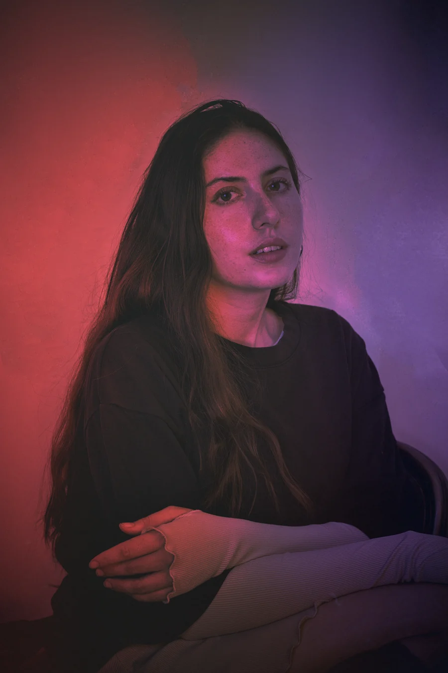 Seated portrait washed in red and violet light
