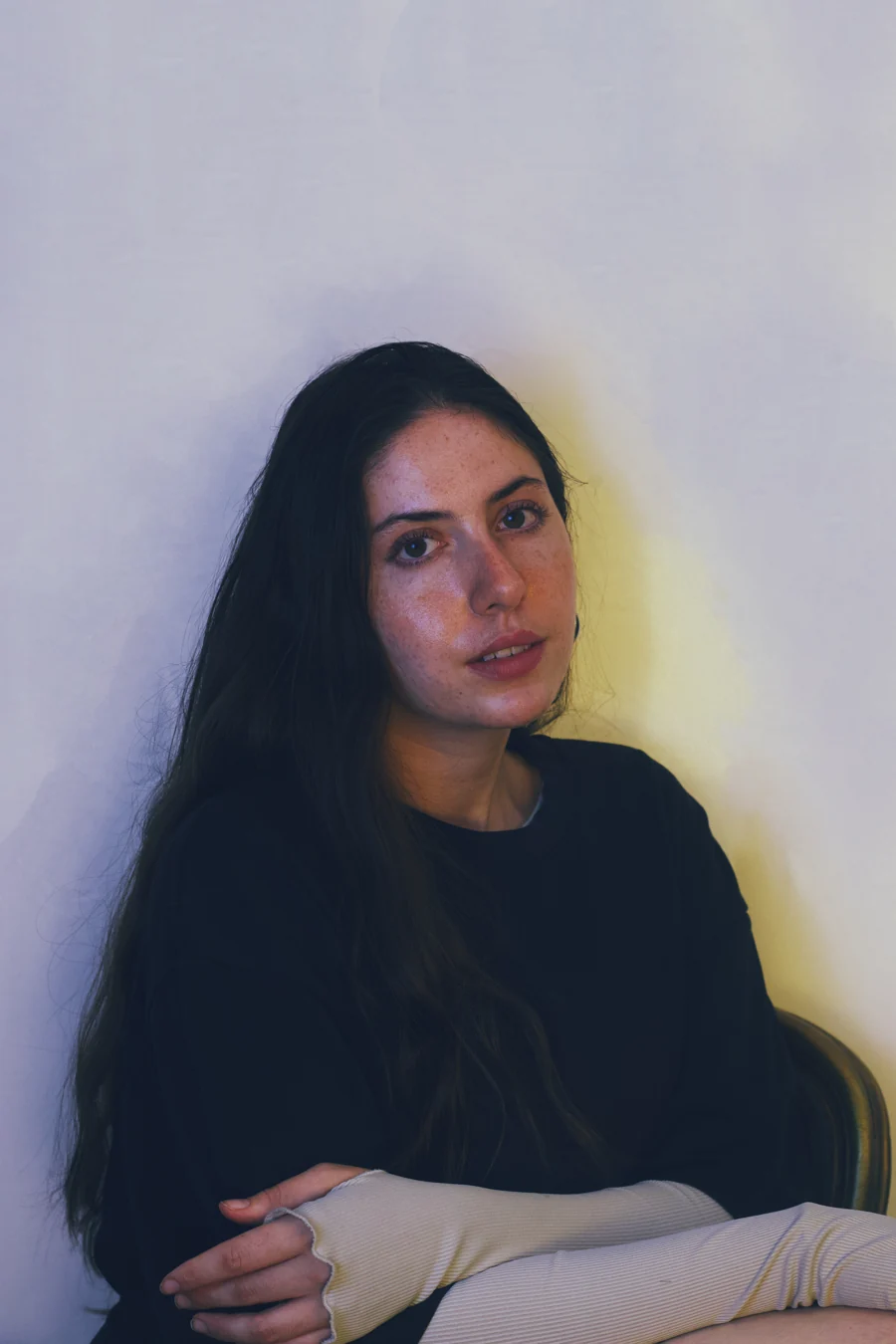 Seated portrait against a pale wall with soft yellow light